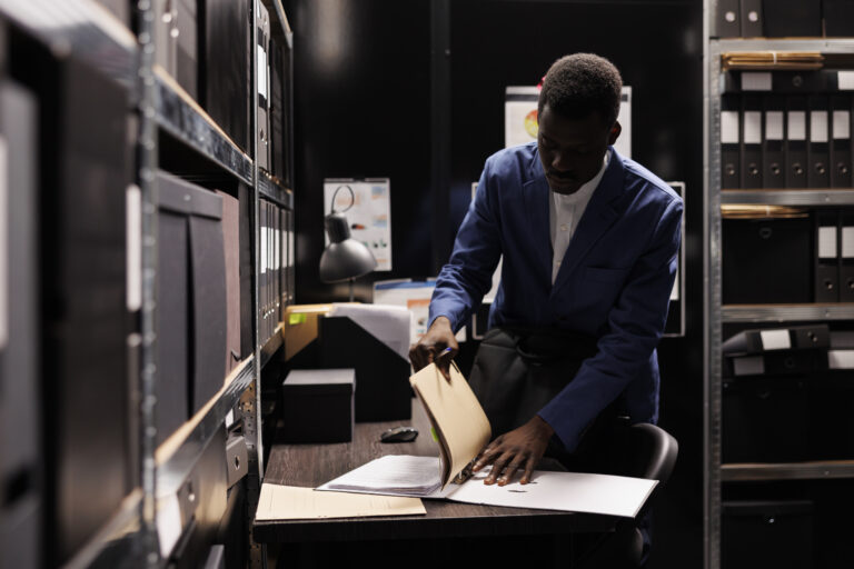 african american manager gathering his stuff preparing leave job late night after working accountancy report file room employee searching bureaucracy record corporate depository