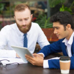pensive colleagues using modern device while taking statistics