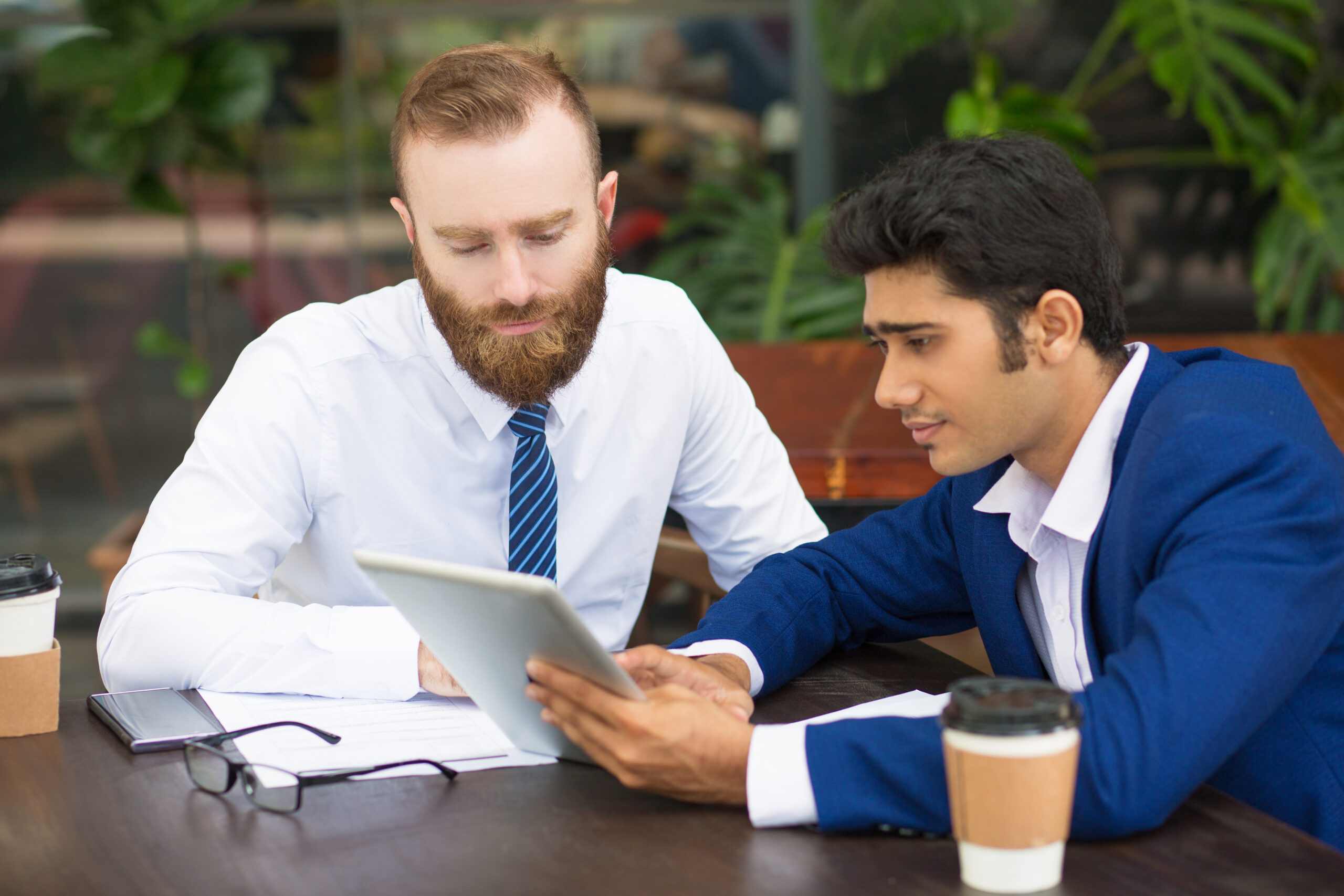 pensive colleagues using modern device while taking statistics scaled